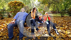 Portrait of family with two children sitting on a bench in beautiful autumn park