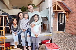 Portrait Of Family Unloading Furniture From Removal Truck Into New Home photo