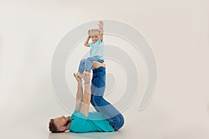 Portrait of family wearing blue T-shirts, jeans. Little smiling girl with short fair hair sitting on mans feet. Family.