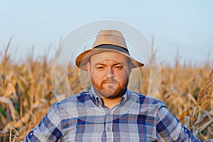 Portrait of a farmer with hat in a field of maize. Man in a rural agricultural environment.