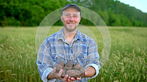 Portrait of farmer holding in hands biological product of potatoes. Concept - Farmer`s market, Organic Farming, Farm