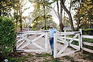 A portrait of farmer walking outdoors on family farm, opening gate.