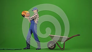 Portrait of farmer in working clothing on chroma key green screen. Gardener standing and holding big pumpkin next to