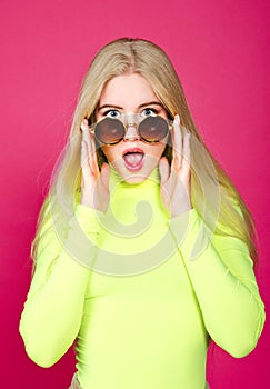 Portrait of fashion blonde surprised smiling model girl young woman wearing stylish with sunglasse isolated on a pink photo