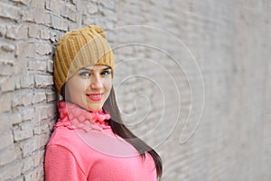 Portrait fashion cool girl in colorful clothes over wooden background wearing a hat and pink sweater