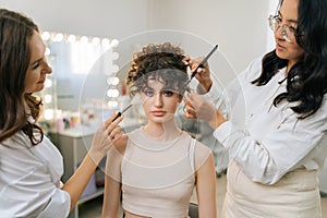 Portrait of fashion female model during having final touch make up in professional beauty studio and looking at camera