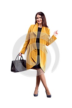 Portrait of fashion girl in yellow coat posing on light backgro