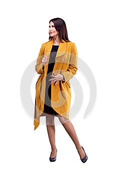 Portrait of fashion girl in yellow coat posing on light backgro