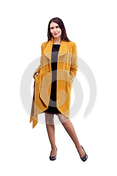 Portrait of fashion girl in yellow coat posing on light backgro