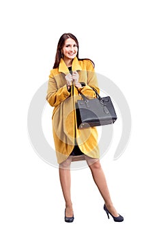 Portrait of fashion girl in yellow coat posing on light backgro