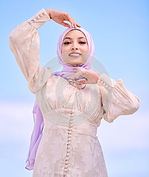 Portrait, fashion or religion with a happy saudi woman on a blue sky background in a scarf for style. Islam, faith or
