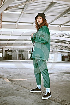 Portrait, fashion or stylish young gen z woman stand in a warehouse with green clothing. Trendy, hipster latino girl