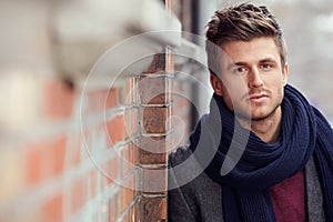 Portrait, fashion and a young man in the city during winter for masculine style while leaning on a wall. Face, trendy