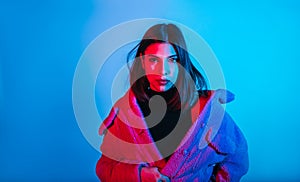 Portrait of fashion young woman in pink jacket in red and blue neon light