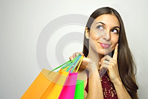 Portrait of a fashionable gorgeous brunette with bags shopper in her hand thinking what to buy and looking to the side the copy sp