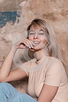 Portrait of a fashionable happy young woman with positive beautiful smile in a vintage T-shirt in blue trendy jeans on a