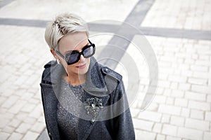 Portrait of fashionable mature woman with short blonde hair wearing stylish gray wool coat with lapels and shoulder photo