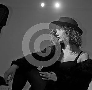 Portrait of a fashionable model with black fur sitting in a green chair in studio. Close up Portrait of young beautiful woman