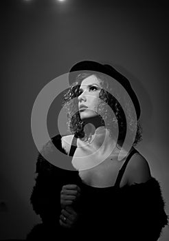 Portrait of a fashionable model with black fur sitting in a green chair in studio. Close up Portrait of young beautiful woman