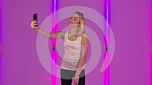 Portrait of fashionable model talking for video chat using mobile phone and rejoice. Young blonde woman in white casual