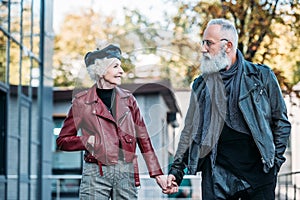 portrait of fashionable senior couple holding hands and looking at each other