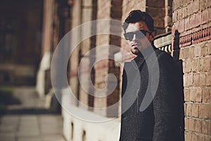 Portrait of fashionable well dressed man with beard posing outdoors looking away.