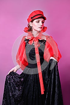 Portrait of fashionable young girl in red hat and black dress. pink background