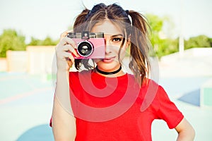 Portrait of fashionable young redhead girl photographer with pink vintage film camera.