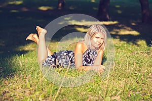 Portrait of fashionable young sensual blonde woman in garden sitting on the grass