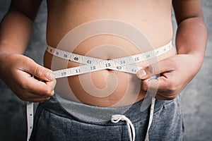 Portrait fat boy measuring tape of stomach