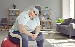 Portrait of a fat confident woman wearing sportswear sitting on a fit ball at home.