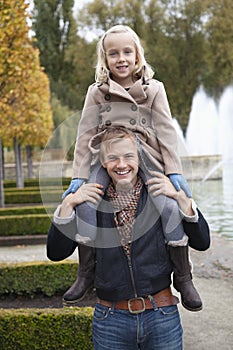 Portrait of father carrying daughter on his shoulders at park