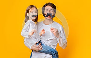 Portrait of father and daughter having fun over yellow background