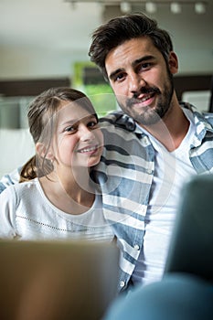 Portrait of father and daughter using laptop and digital tablet in the living room