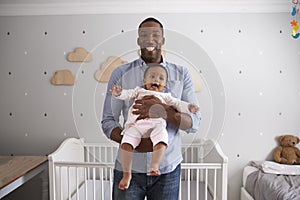 Portrait Of Father Holding Baby Daughter In Nursery