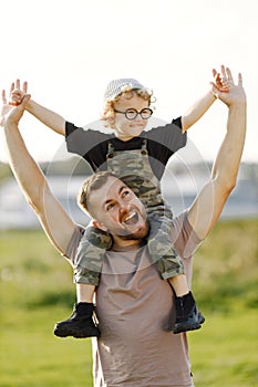 Portrait of father holding his son on a shoulders outdoors