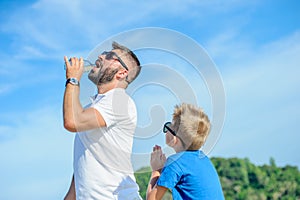 Portrait of father non-giving water to his thirsty handsome boy on the desert tropical beach.