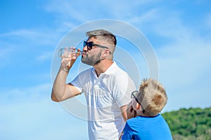 Portrait of father non-giving water to his thirsty handsome boy on the desert tropical beach.