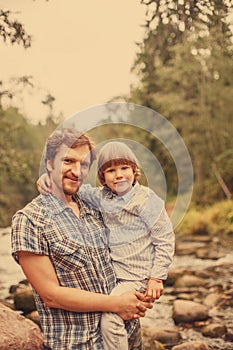 Portrait of a father and son on the background of nature. Dad and child in a field at sunset