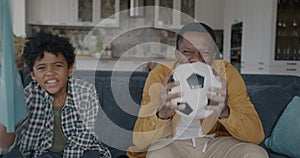 Portrait of father and son excited African American people watching soccer on TV at home cheering having fun