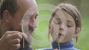 Portrait of a father and son with a flower dandelion. The bearded father playing with his son.