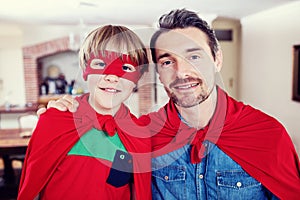 Portrait of father and son pretending to be superhero in living room