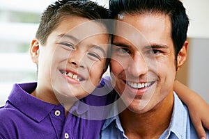 Portrait Of Father And Son Sitting On Sofa At Home