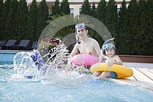 Portrait of father and son in snorkeling gear sitting by the edge of the pool and splashing