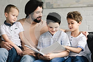 portrait of father and sons reading book together