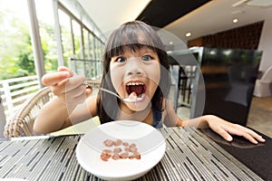 Portrait of feeling happy a young girl having breakfast on table