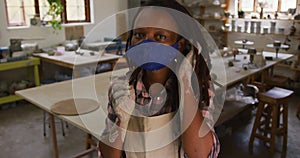 Portrait of female african american potter with dirty hands in clay at pottery studio