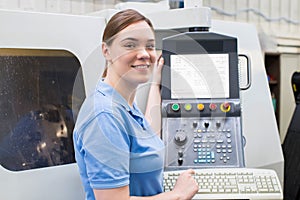 Portrait Of Female Apprentice Engineer Operating CNC Machine In