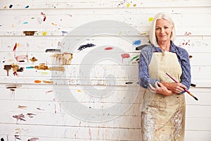 Portrait Of Female Artist Against Paint Covered Wall