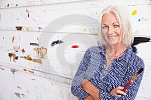 Portrait Of Female Artist Against Paint Covered Wall